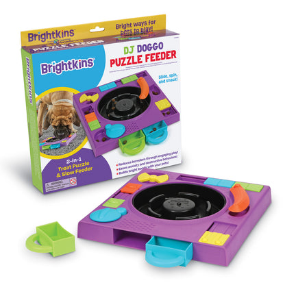A purple turntable style food puzzle for dogs beside the product's box