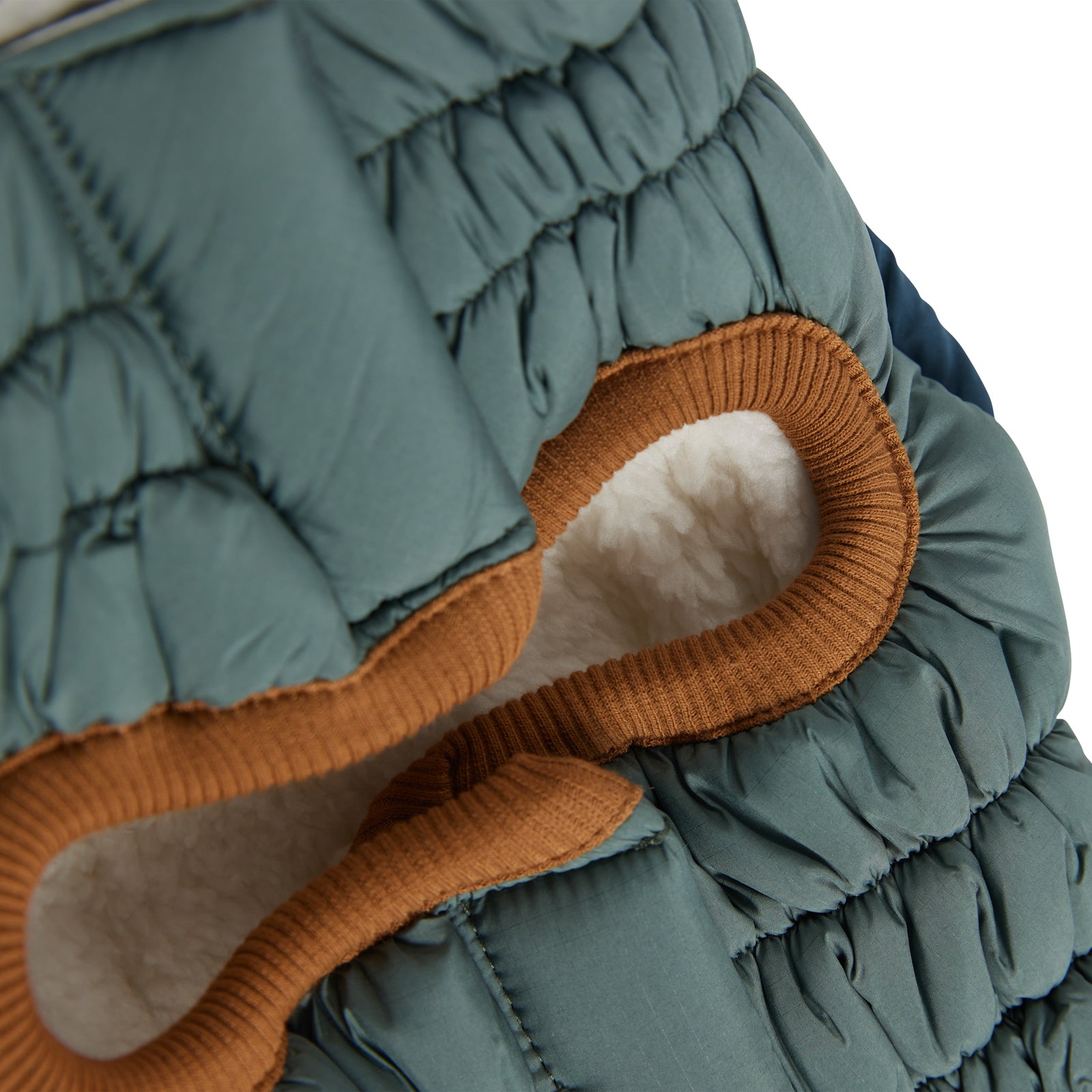 closeup shot of the underside of a sage colored puffer with brown trim for dogs