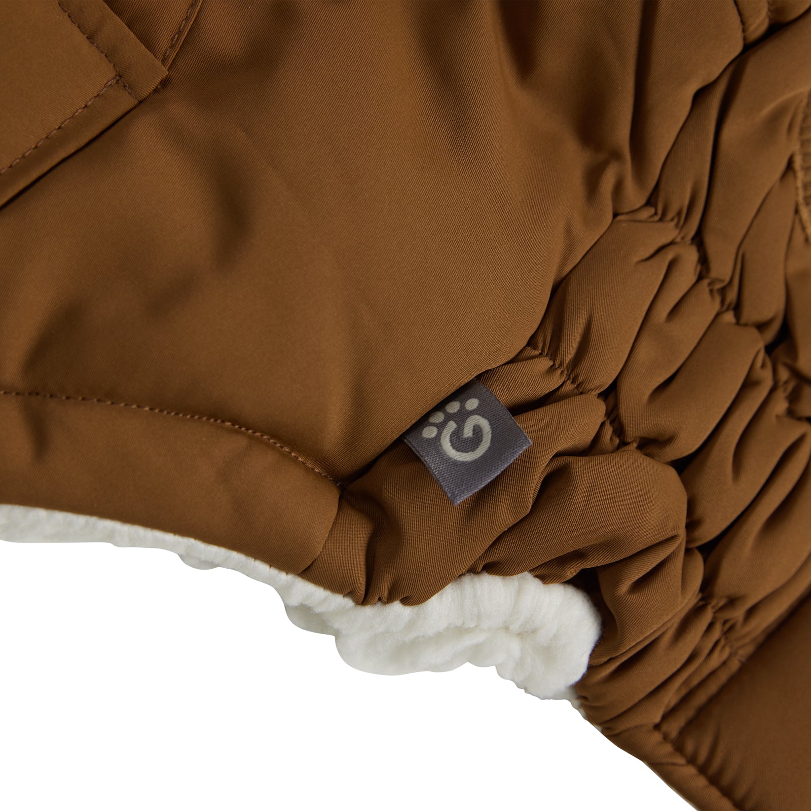 a closeup of the edge of a white fleece lined brown parka for dogs