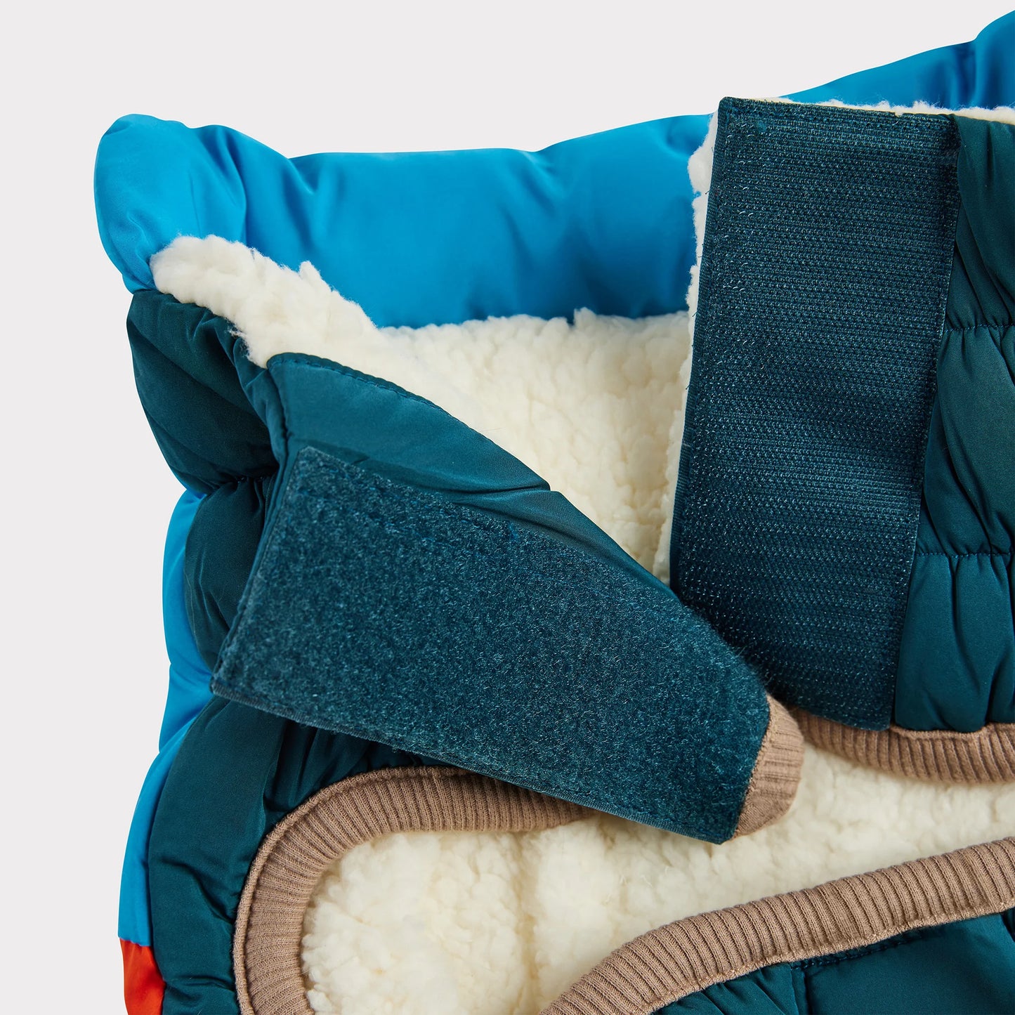 detailed view of the neck of a blue, orange and teal color blocked puffer jacket for dogs 