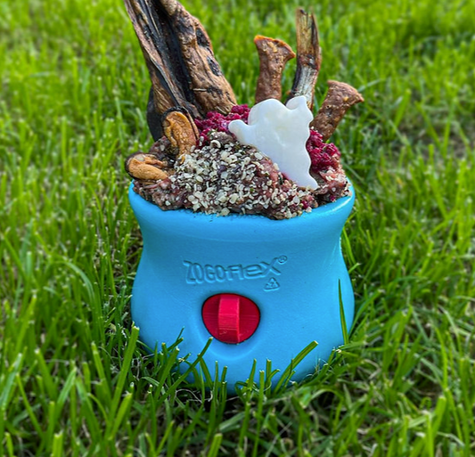 A blue Toppl work-to-eat dog toy with a red Stopple stopper, filled with dog treats
