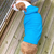 top view of a brown and white pit bull type dog standing on a wooden deck wearing a blue hoodie