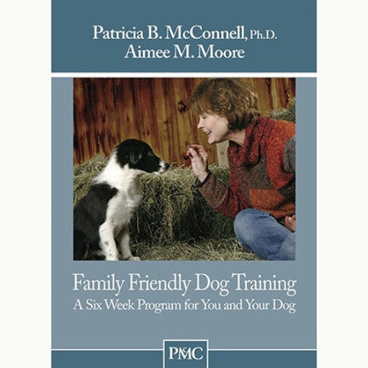 The blue cover of a book with a photo of a woman offering a treat to a small white and black dog