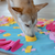 a dog sniffing a blue , yellow, pink and white snuffle mat