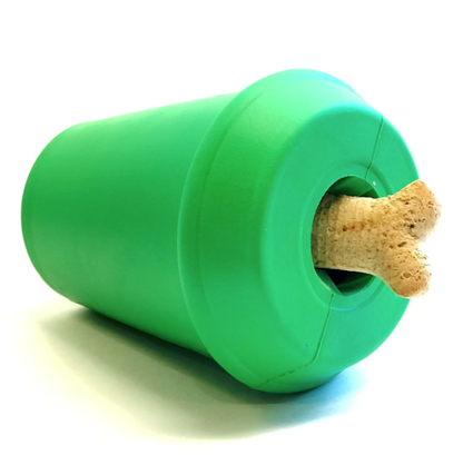 a greed rubber coffee cup shaped dog toy on its side with a dog treat stuck in the top