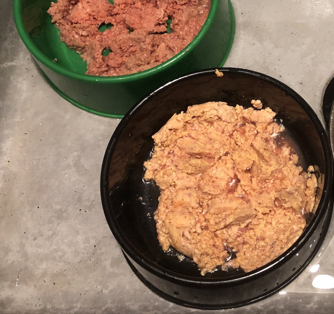 a green bowl and a black bowl containing raw dog food