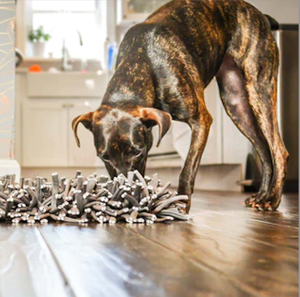 a large brindle dog sniffing a grey snuffle mat